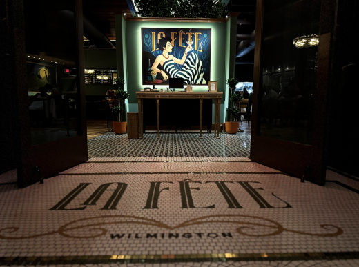 Elegant entrance to La Fête French restaurant in Wilmington, Delaware, featuring the signature welcome mat and French poster artwork